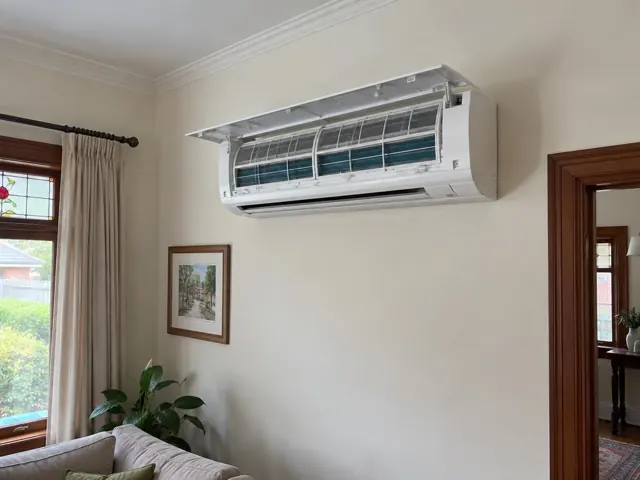 Clean split system with open front panel and visible filters on a cream wall in a living room in Blair Athol