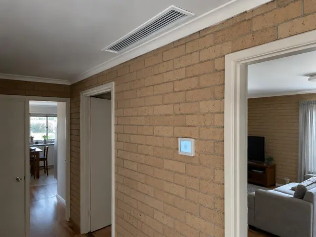 Hallway with ceiling air grille and wall zone controller on a brick wall in Clearview